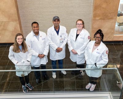 Indoor group portrait of five physiology graduate students.